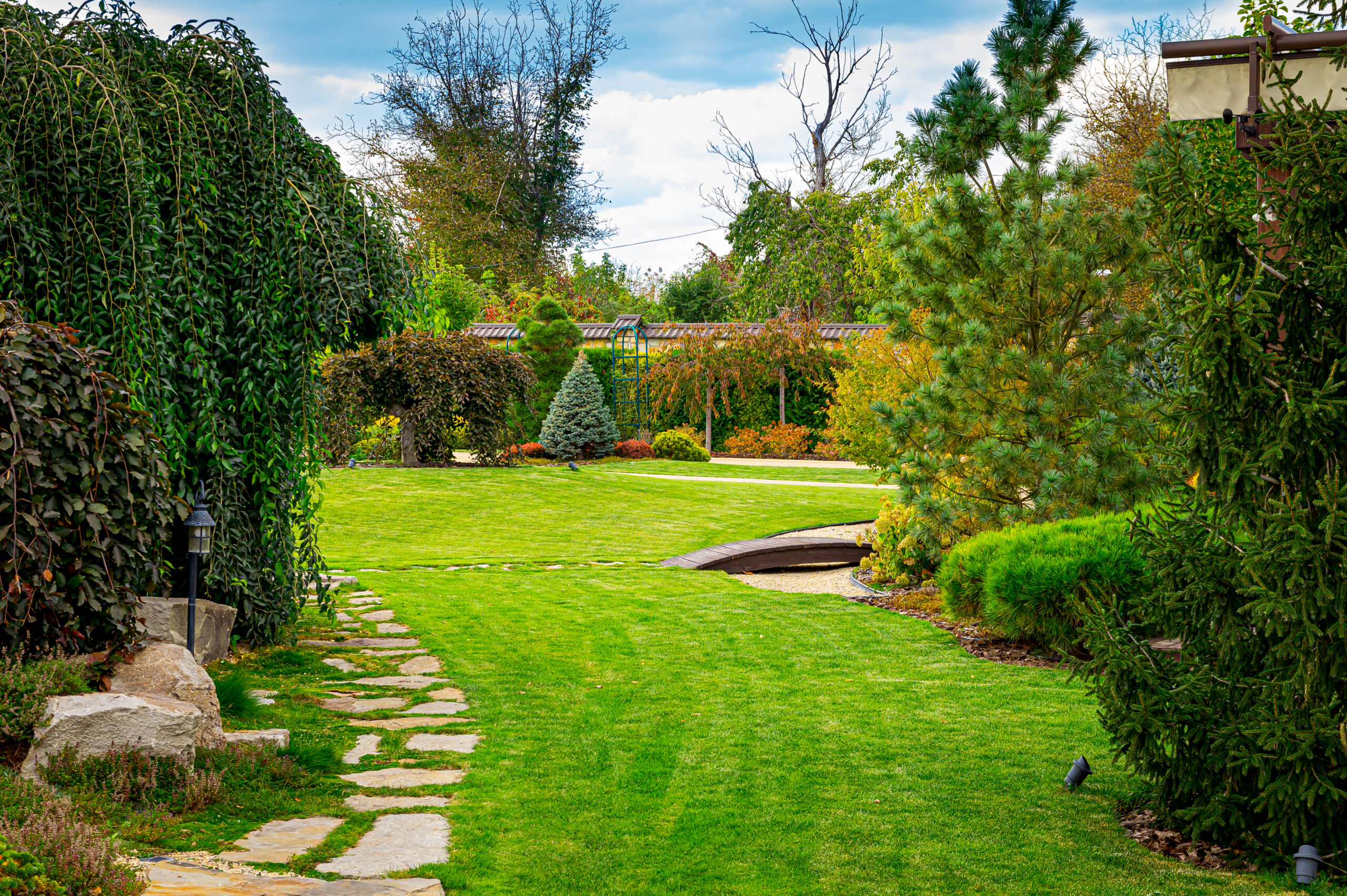 Front yard, landscape design with multicolored shrubs intersecting with bright green lawns behind the house is a modern, garden care service, green grass with a beautiful yard for the background.
