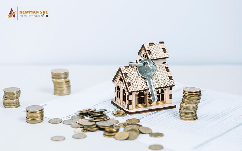 A miniature house and coins on a paper.